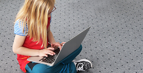 Mädchen beschäftigt sich mit einem Notebook auf dem Boden
