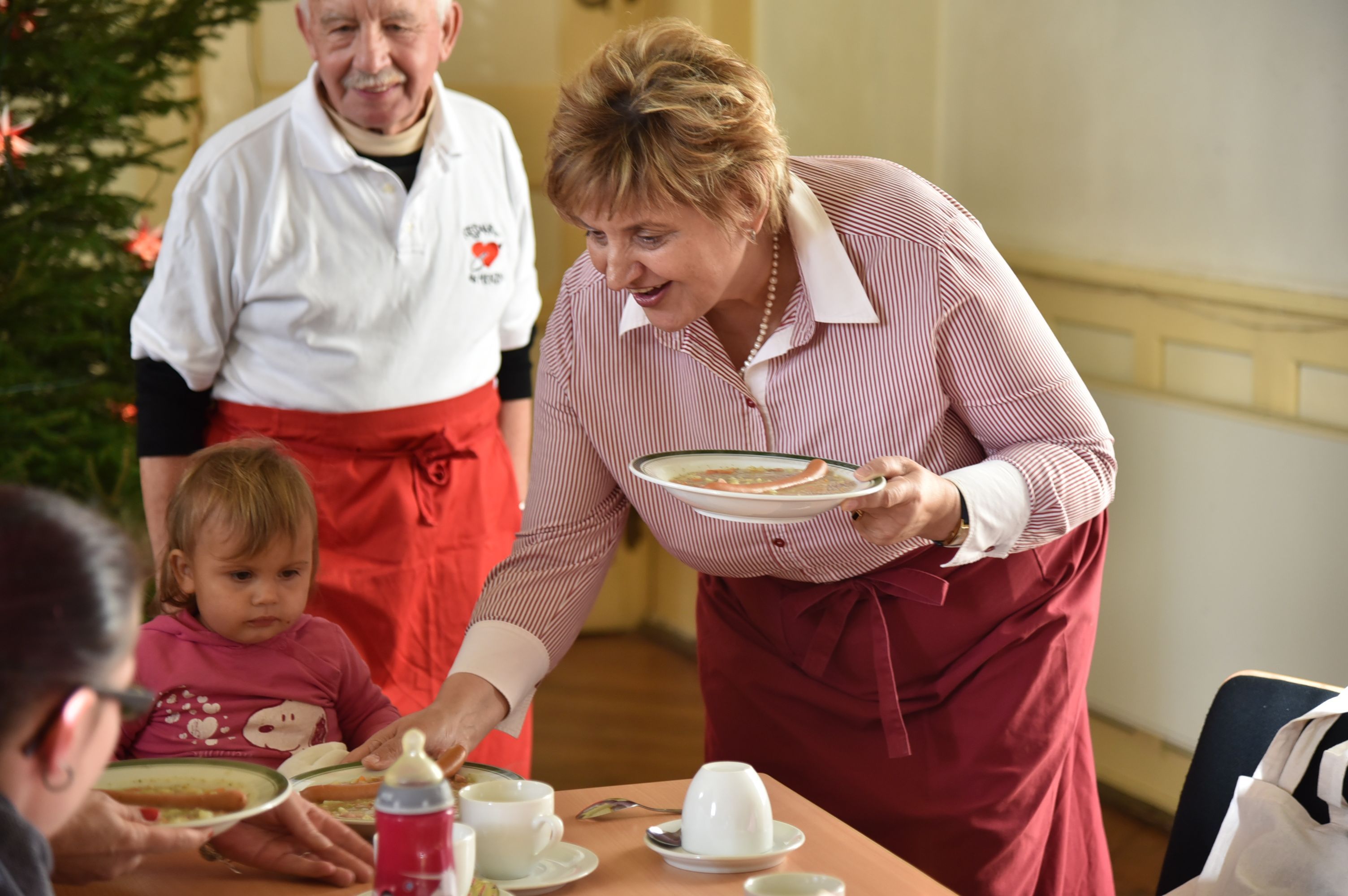 Birgit Diezel reicht einem Gast einen Teller Suppe am Tisch