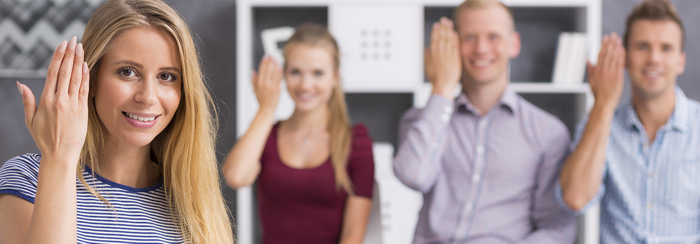 Vier junge Menschen, die die Gebärde Willkommen zeigen