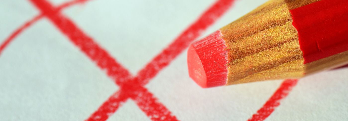 Ein roter Buntstift, der ein Wahlkreuz malt.