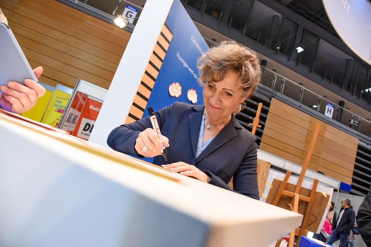 Landtagspräsidentin Birgit Keller beim Unterschreiben von Autogrammkarten.
